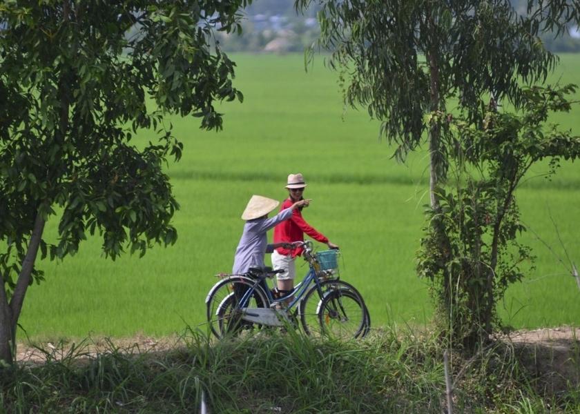 Cycling under the shade of coconut palms on a small concrete path in Ben Tre, Mekong Delta.