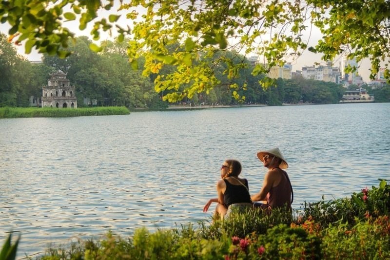 A tourist couple admires the tranquil beauty of Hoan Kiem Lake