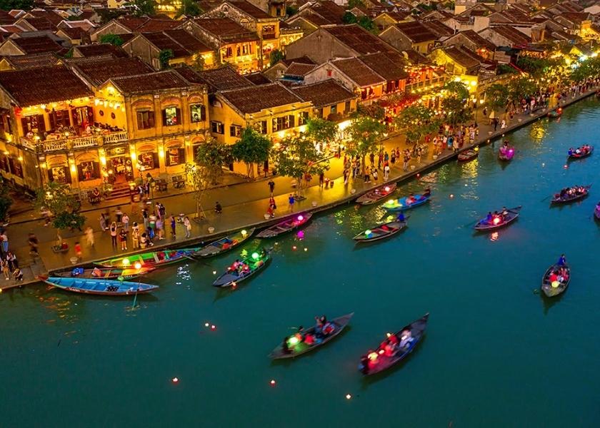 An aerial view of Hoi An Ancient Town at night with lantern-lit boats on the Hoai River in Vietnam.