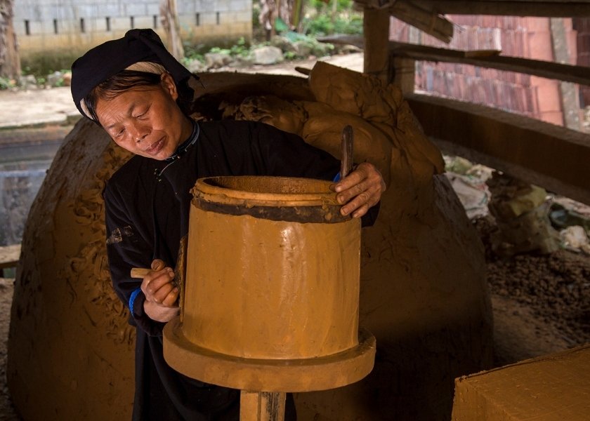 Nung artisans in Lung Ri village are meticulously carving and cutting terracotta surfaces to create yin-yang roof shapes.